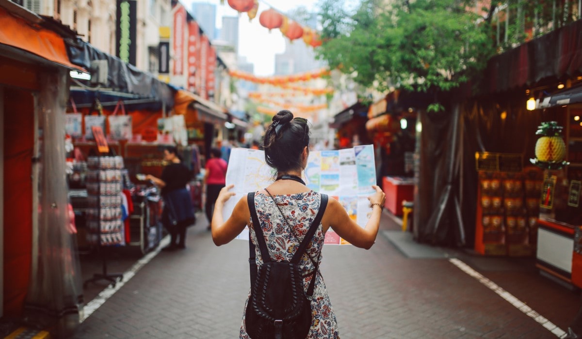 Solo traveller holding a map in the middle of a street market
